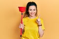 Young hispanic woman holding toilet plunger smiling with an idea or question pointing finger with happy face, number one Royalty Free Stock Photo