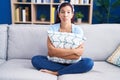 Young hispanic woman hugging pillow sitting on the sofa depressed and worry for distress, crying angry and afraid Royalty Free Stock Photo