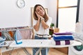 Young hispanic woman ironing clothes at laundry room sleeping tired dreaming and posing with hands together while smiling with Royalty Free Stock Photo