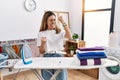 Young hispanic woman ironing clothes at laundry room very happy and excited doing winner gesture with arms raised, smiling and Royalty Free Stock Photo