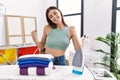 Young hispanic woman ironing clothes at laundry room very happy and excited doing winner gesture with arms raised, smiling and Royalty Free Stock Photo