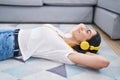 Young hispanic woman listening to music lying on floor at home Royalty Free Stock Photo