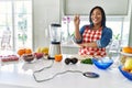 Young hispanic woman making healthy smoothie smiling with happy face winking at the camera doing victory sign Royalty Free Stock Photo