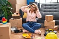 Young hispanic woman moving to a new home sitting on the floor smiling pulling ears with fingers, funny gesture Royalty Free Stock Photo