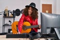 Young hispanic woman musician composing song playing classical guitar at music studio Royalty Free Stock Photo