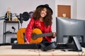 Young hispanic woman musician composing song playing classical guitar at music studio Royalty Free Stock Photo