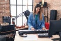Young hispanic woman musician playing piano keyboard at music studio Royalty Free Stock Photo
