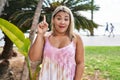 Young hispanic woman outdoors by the park smiling with an idea or question pointing finger with happy face, number one Royalty Free Stock Photo