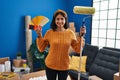 Young hispanic woman painting home walls with paint roller smiling with a happy and cool smile on face Royalty Free Stock Photo