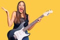 Young hispanic woman playing electric guitar celebrating victory with happy smile and winner expression with raised hands Royalty Free Stock Photo