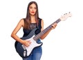 Young hispanic woman playing electric guitar thinking attitude and sober expression looking self confident Royalty Free Stock Photo