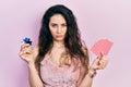 Young hispanic woman playing poker holding casino chips and cards skeptic and nervous, frowning upset because of problem Royalty Free Stock Photo