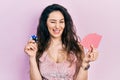 Young hispanic woman playing poker holding casino chips and cards winking looking at the camera with sexy expression, cheerful and Royalty Free Stock Photo