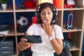 Young hispanic woman playing video games with smartphone covering mouth with hand, shocked and afraid for mistake Royalty Free Stock Photo