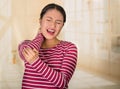 Young hispanic woman posing for camera showing signs of neck pain, holding hands on painful body part, injury concept Royalty Free Stock Photo