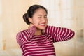 Young hispanic woman posing for camera showing signs of neck pain, holding hands on painful body part, injury concept Royalty Free Stock Photo