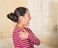 Young hispanic woman posing for camera showing signs of shoulder pain, holding hands on painful body part, injury Royalty Free Stock Photo