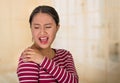 Young hispanic woman posing for camera showing signs of shoulder pain, holding hands on painful body part, injury Royalty Free Stock Photo