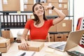 Young hispanic woman preparing order working at storehouse smiling pointing to head with one finger, great idea or thought, good