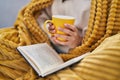 Young hispanic woman reading book and drinking coffee at home Royalty Free Stock Photo