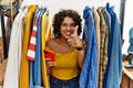 Young hispanic woman searching clothes on clothing rack using smartphone pointing fingers to camera with happy and funny face Royalty Free Stock Photo