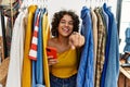 Young hispanic woman searching clothes on clothing rack using smartphone pointing to you and the camera with fingers, smiling Royalty Free Stock Photo