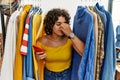 Young hispanic woman searching clothes on clothing rack using smartphone tired rubbing nose and eyes feeling fatigue and headache Royalty Free Stock Photo