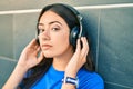 Young hispanic woman with serious expression listening to music using headphones at the city Royalty Free Stock Photo