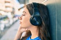 Young hispanic woman with serious expression listening to music using headphones at the city Royalty Free Stock Photo