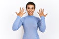 Young hispanic woman with short hair standing over isolated background showing and pointing up with fingers number ten while Royalty Free Stock Photo