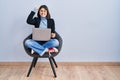 Young hispanic woman sitting on chair using computer laptop angry and mad raising fist frustrated and furious while shouting with Royalty Free Stock Photo