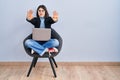 Young hispanic woman sitting on chair using computer laptop doing stop gesture with hands palms, angry and frustration expression Royalty Free Stock Photo