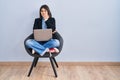 Young hispanic woman sitting on chair using computer laptop looking stressed and nervous with hands on mouth biting nails Royalty Free Stock Photo