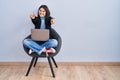 Young hispanic woman sitting on chair using computer laptop pointing to you and the camera with fingers, smiling positive and Royalty Free Stock Photo