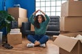 Young hispanic woman sitting on the floor at new home making fish face with mouth and squinting eyes, crazy and comical