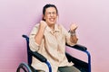 Young hispanic woman sitting on wheelchair celebrating surprised and amazed for success with arms raised and eyes closed