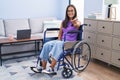 Young hispanic woman sitting on wheelchair at home smiling friendly offering handshake as greeting and welcoming Royalty Free Stock Photo