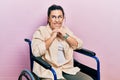 Young hispanic woman sitting on wheelchair laughing nervous and excited with hands on chin looking to the side Royalty Free Stock Photo