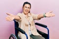 Young hispanic woman sitting on wheelchair looking at the camera smiling with open arms for hug Royalty Free Stock Photo