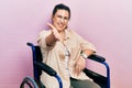 Young hispanic woman sitting on wheelchair smiling friendly offering handshake as greeting and welcoming Royalty Free Stock Photo