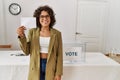 Young hispanic woman smiling confident holding vote at electoral college