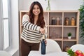 Young hispanic woman smiling confident uncorking red wine bottle at home Royalty Free Stock Photo