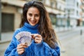 Young hispanic woman smiling happy counting sweden krone banknotes at the city