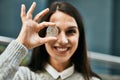 Young hispanic woman smiling happy holding ethereum crypto coin over eye at the city Royalty Free Stock Photo