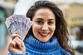 Young hispanic woman smiling happy holding sweden krone banknotes at the city