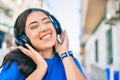 Young hispanic woman smiling happy listening to music using headphones walking at the city Royalty Free Stock Photo