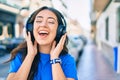 Young hispanic woman smiling happy listening to music using headphones walking at the city Royalty Free Stock Photo