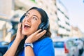 Young hispanic woman smiling happy listening to music using headphones walking at the city Royalty Free Stock Photo