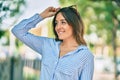 Young hispanic woman smiling happy touching her sunglasses at the park