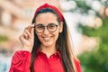 Young hispanic woman smiling happy touching his glasses at the city